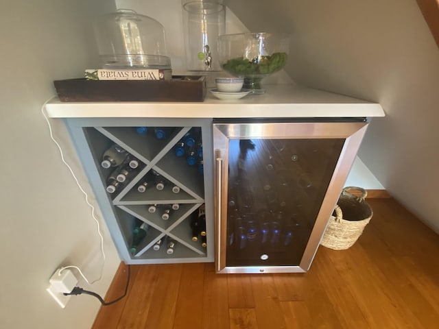 bar area featuring wood finished floors and beverage cooler