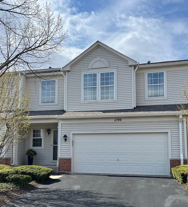 traditional home with an attached garage, driveway, and brick siding