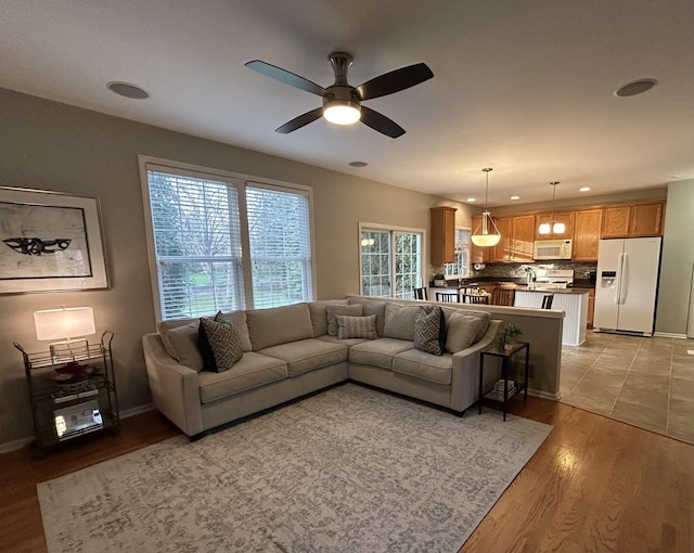 living area featuring recessed lighting, ceiling fan, baseboards, and light wood finished floors