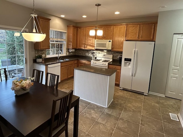 kitchen featuring dark countertops, a sink, backsplash, and white appliances