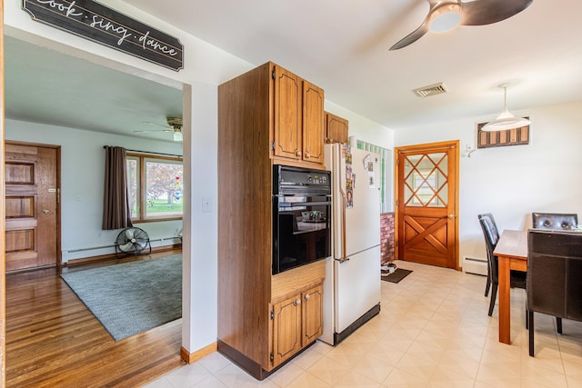 kitchen with ceiling fan, black oven, brown cabinetry, freestanding refrigerator, and visible vents