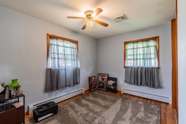 unfurnished room featuring a wealth of natural light, a ceiling fan, a baseboard heating unit, and visible vents