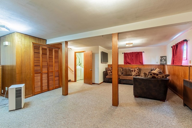 carpeted living area featuring wood walls and washer / dryer