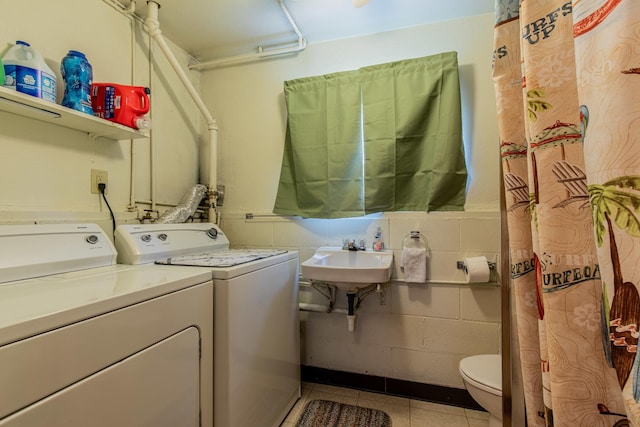 washroom featuring laundry area, a sink, washer and clothes dryer, and tile patterned floors