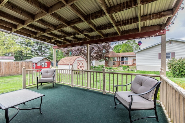 view of patio / terrace with an outdoor structure, fence, a wooden deck, a storage shed, and a residential view