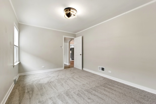 carpeted empty room with arched walkways, ornamental molding, baseboards, and visible vents