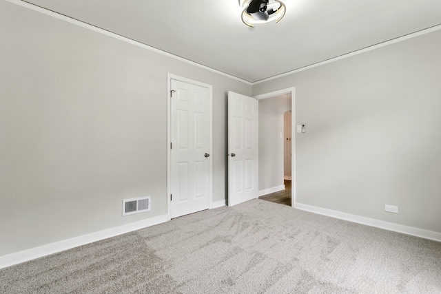 unfurnished bedroom featuring visible vents, ornamental molding, carpet, and baseboards