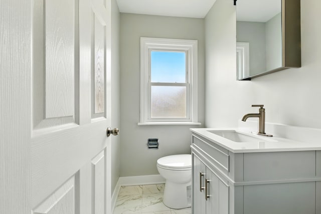 half bathroom with baseboards, vanity, toilet, and marble finish floor