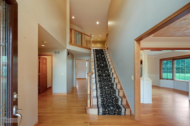 stairs featuring visible vents, wood finished floors, ornate columns, ornamental molding, and recessed lighting