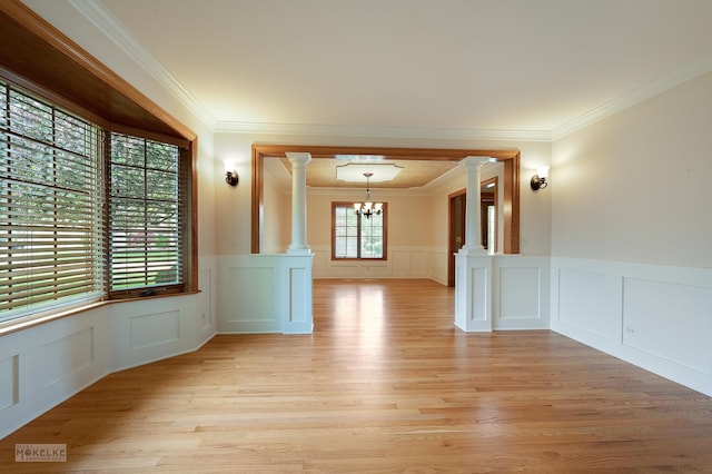 unfurnished room featuring a wainscoted wall, decorative columns, a decorative wall, and a notable chandelier