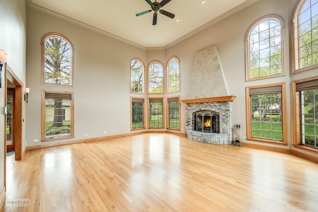 unfurnished living room featuring a towering ceiling, a healthy amount of sunlight, and ceiling fan
