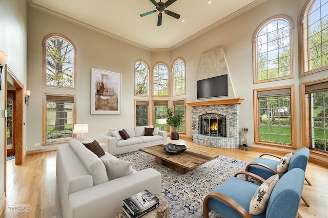 living area with a ceiling fan, plenty of natural light, wood finished floors, and a towering ceiling
