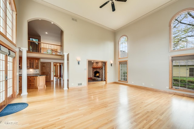 unfurnished living room with a healthy amount of sunlight, ceiling fan, visible vents, and a towering ceiling