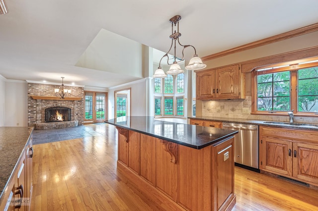 kitchen featuring a sink, a kitchen breakfast bar, light wood-style flooring, stainless steel dishwasher, and ornamental molding
