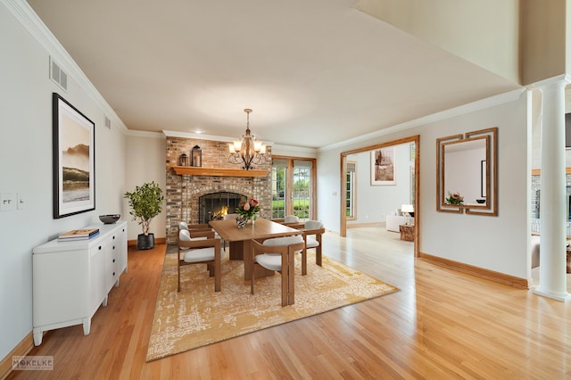 dining area with a brick fireplace, baseboards, decorative columns, and light wood-style flooring
