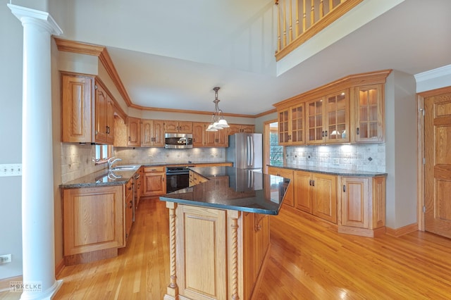 kitchen featuring a sink, light wood-style floors, stainless steel appliances, tasteful backsplash, and ornate columns