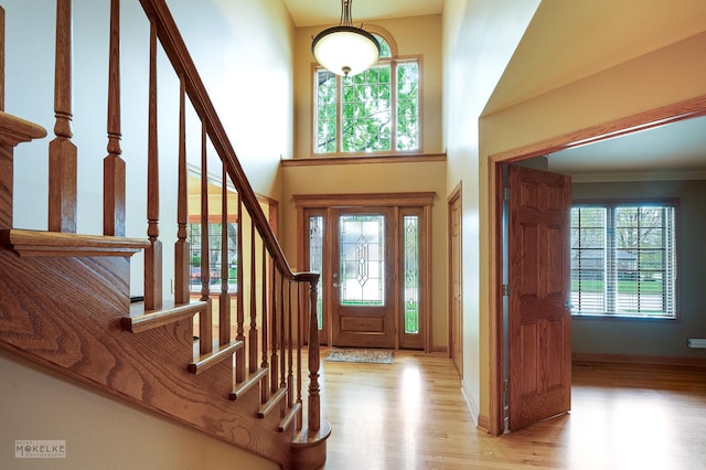 foyer featuring baseboards, a high ceiling, wood finished floors, and stairway