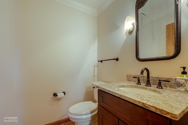 half bathroom with vanity, ornamental molding, and toilet