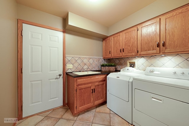 clothes washing area with a sink, cabinet space, washing machine and dryer, and light tile patterned flooring