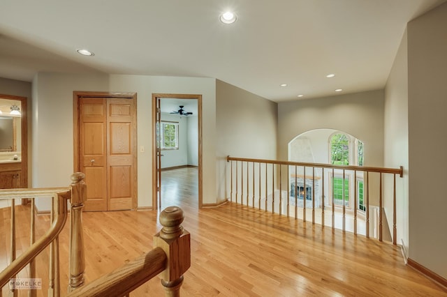 hall with recessed lighting, an upstairs landing, and light wood finished floors