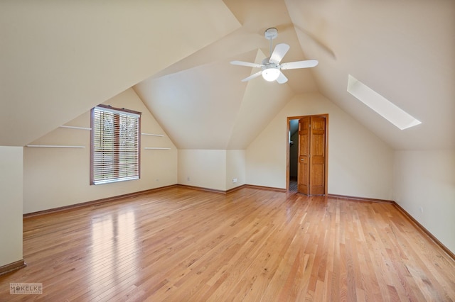 bonus room with baseboards, lofted ceiling with skylight, ceiling fan, and wood finished floors