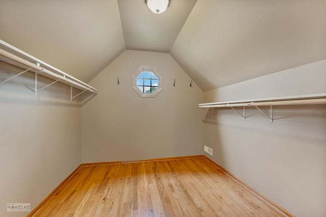 spacious closet featuring wood-type flooring, visible vents, and vaulted ceiling