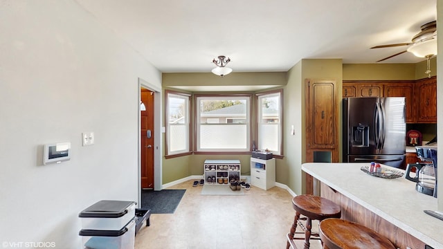 2818 Brentwood Dr, Racine, WI 53403 - kitchen with stainless steel fridge, light countertops, baseboards, a breakfast bar, and a ceiling fan
