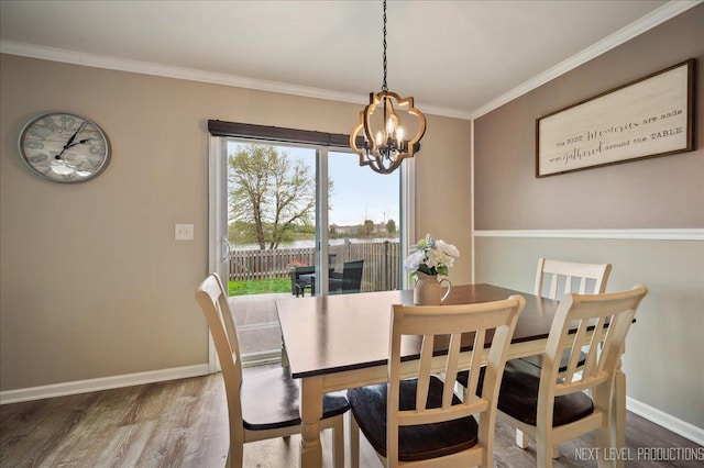 dining room with a chandelier, wood finished floors, crown molding, and baseboards