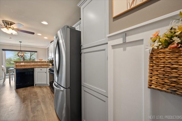 kitchen featuring black appliances, a peninsula, wood finished floors, a sink, and ceiling fan