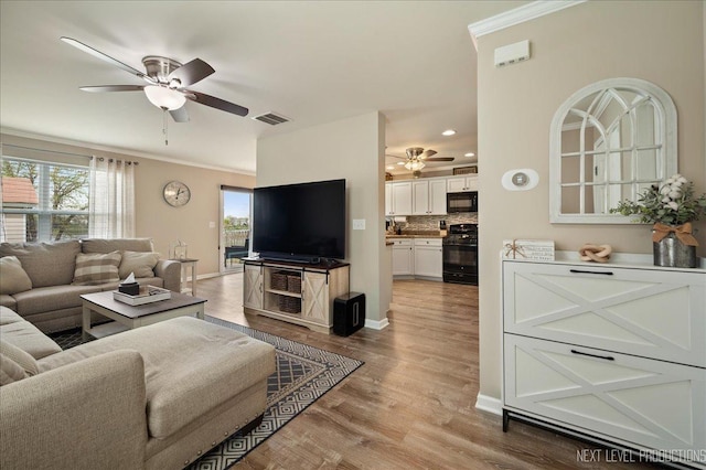 living area with a ceiling fan, wood finished floors, baseboards, crown molding, and recessed lighting