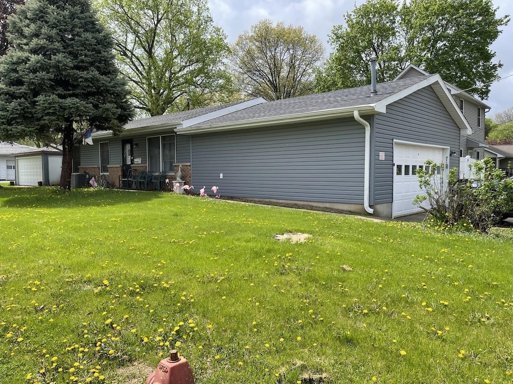 exterior space featuring a lawn, central AC unit, and a garage