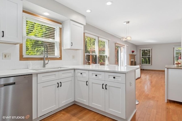 kitchen featuring stainless steel dishwasher, a peninsula, a sink, plenty of natural light, and recessed lighting