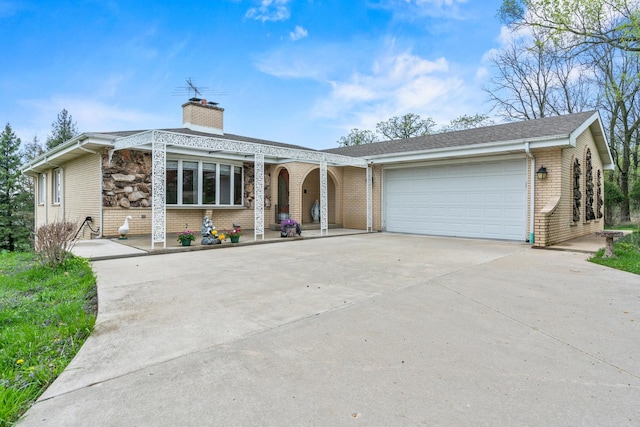 view of front of house with brick siding, driveway, a chimney, and an attached garage