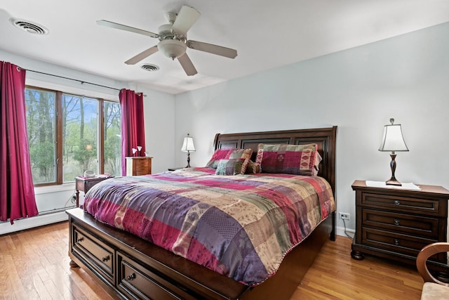 bedroom with hardwood / wood-style flooring, ceiling fan, and a baseboard heating unit