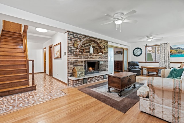 living room with ceiling fan, a fireplace, wood finished floors, and stairs