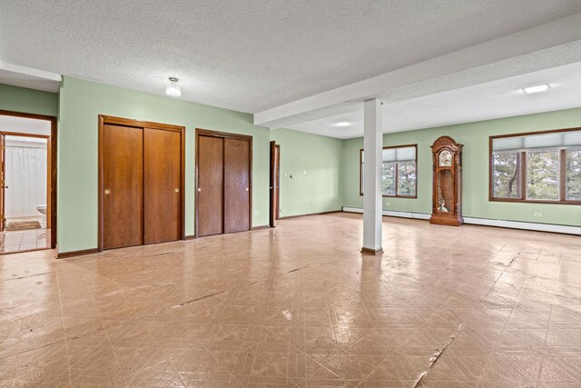 unfurnished living room featuring baseboards, a baseboard radiator, tile patterned floors, and a textured ceiling