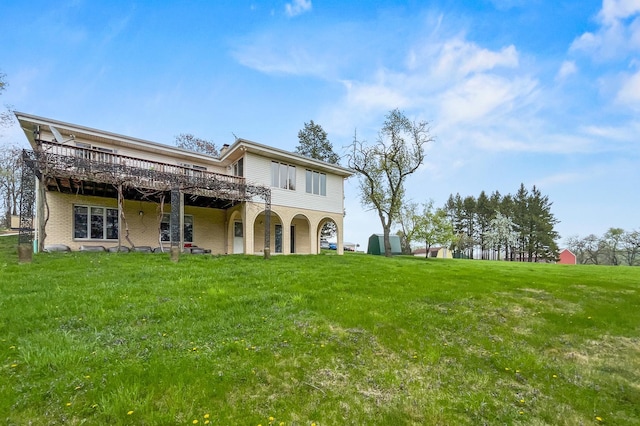 rear view of house with a lawn, a deck, and brick siding