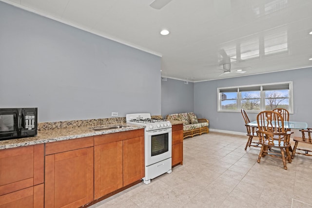 kitchen featuring white range with gas stovetop, a ceiling fan, black microwave, crown molding, and light stone countertops