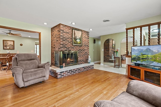 living room with a brick fireplace, wood finished floors, ceiling fan, and recessed lighting