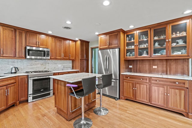 kitchen with appliances with stainless steel finishes, brown cabinets, light wood-style flooring, and recessed lighting