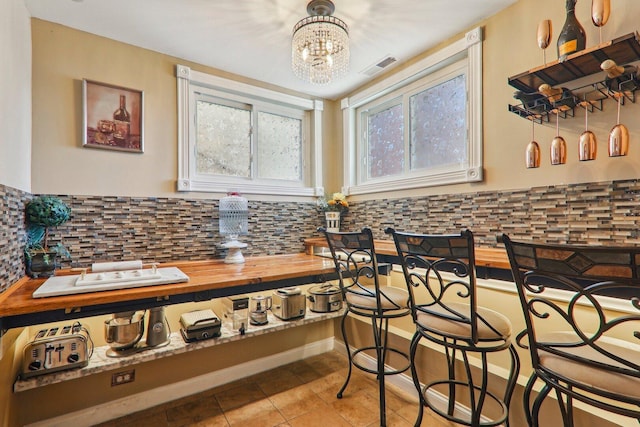 708 N Rockwell St, Chicago, IL 60612 - kitchen featuring visible vents, decorative backsplash, a chandelier, and light tile patterned flooring