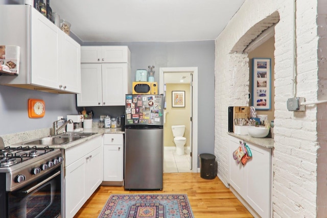 708 N Rockwell St, Chicago, IL 60612 - kitchen featuring appliances with stainless steel finishes, a sink, light countertops, light wood-style floors, and white cabinetry