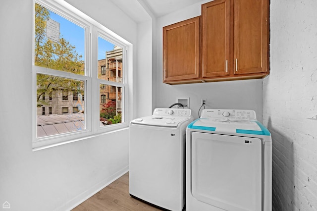 washroom with washer and dryer, cabinet space, light wood-type flooring, and baseboards