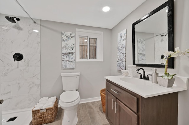 bathroom with a shower, toilet, vanity, and baseboards