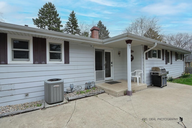 ranch-style house with central AC unit, a chimney, and a patio area