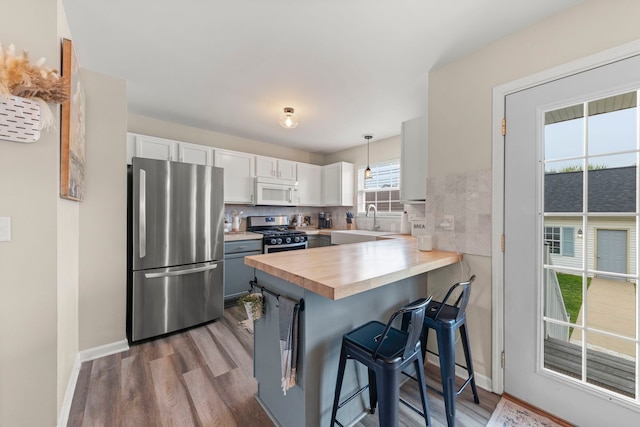 711 W Benham St, Kirkland, IL 60146 - kitchen with appliances with stainless steel finishes, a peninsula, dark wood-style flooring, and a kitchen bar