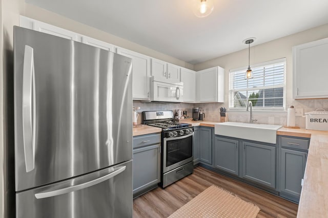 711 W Benham St, Kirkland, IL 60146 - kitchen with stainless steel appliances, wood finished floors, light countertops, backsplash, and white cabinetry