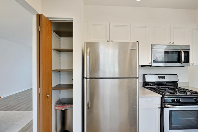 kitchen featuring open shelves, wood finished floors, light countertops, white cabinets, and appliances with stainless steel finishes