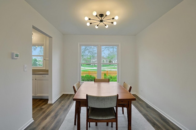 dining room featuring dark wood-style flooring, baseboards, a chandelier, and plenty of natural light