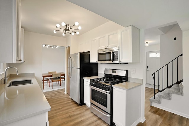 kitchen with white cabinets, a sink, light wood finished floors, light countertops, and stainless steel appliances